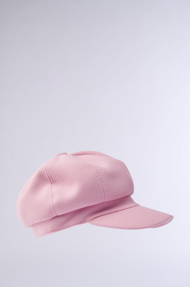 The PRETTY IN PINK BRIM HAT, with its charming soft texture and distinct newsboy style featuring a round crown and short stiff brim, stands out against a plain light gray background, adding a touch of playful style to any wardrobe.