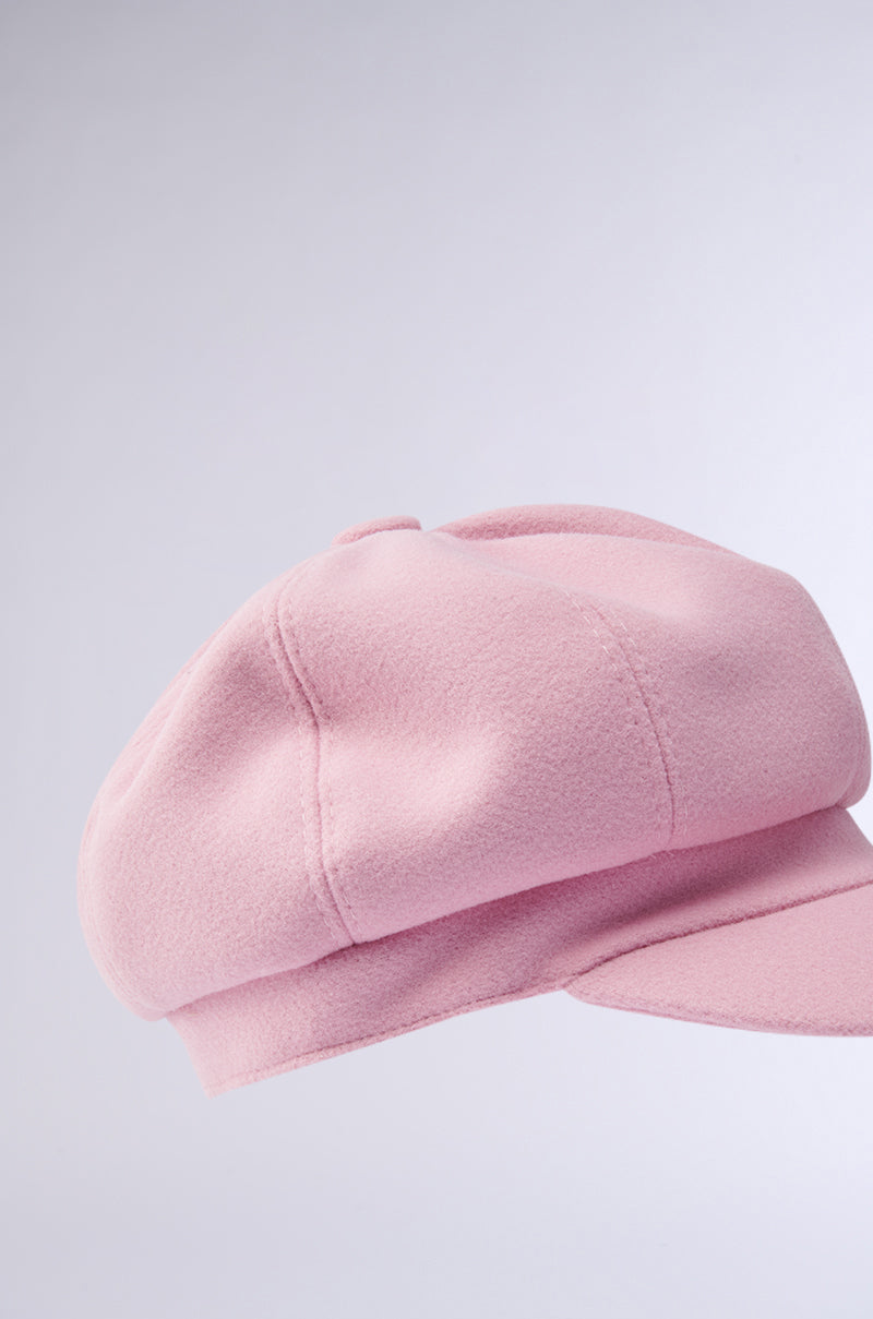 The PRETTY IN PINK BRIM HAT is displayed against a light gray background, showcasing its stylish pink color, soft fabric texture, short stiff brim, and round structured crown that exudes both classic elegance and modern flair.