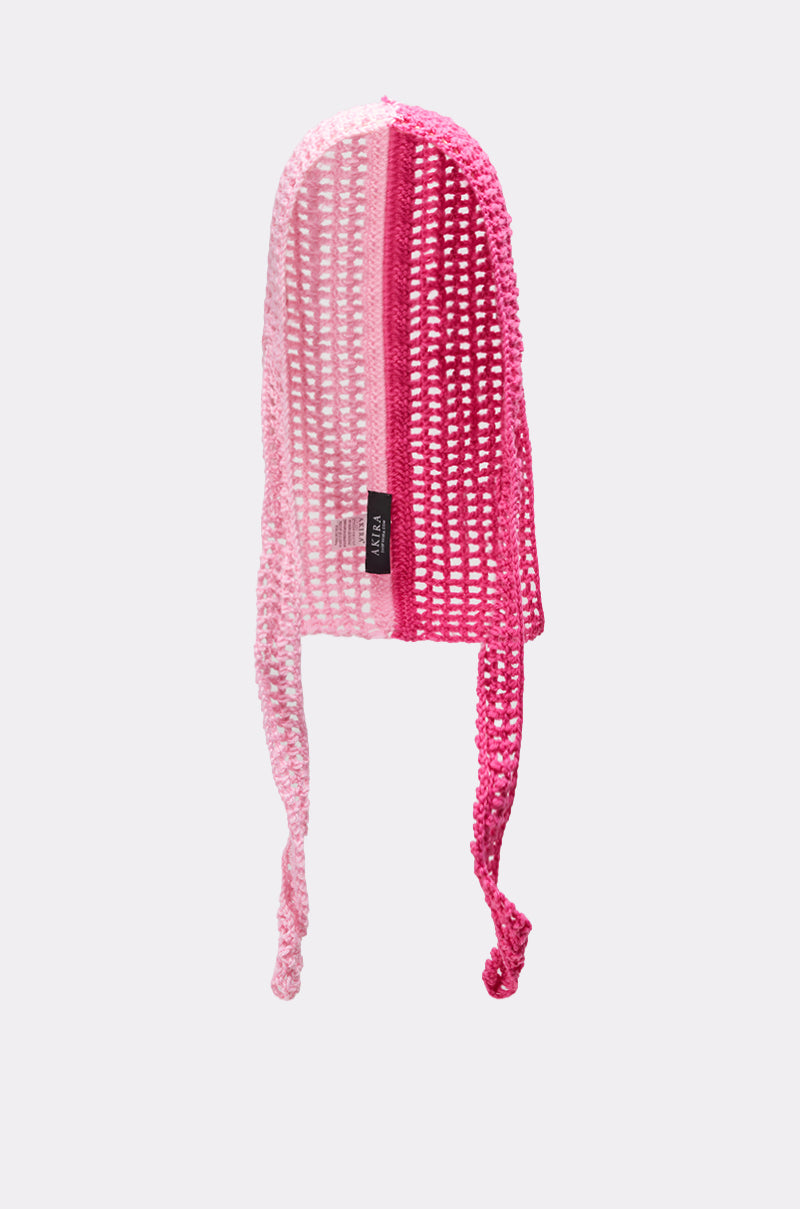 The YOU KNOW WHERE IM AT PINK CROCHET HEAD SCARF features varying shades of pink in an open-weave design, two long ties, and a black side label, shown against a plain light gray background.