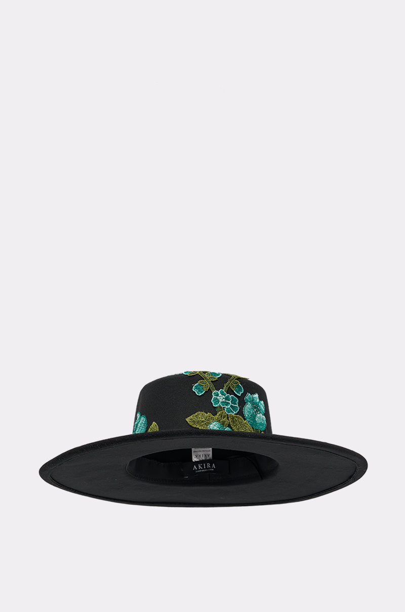 The IN THE FIELD APPLIQUE BRIM HAT has a wide brim and turquoise and green floral embroidery on the crown, shown against a plain light background. 1
