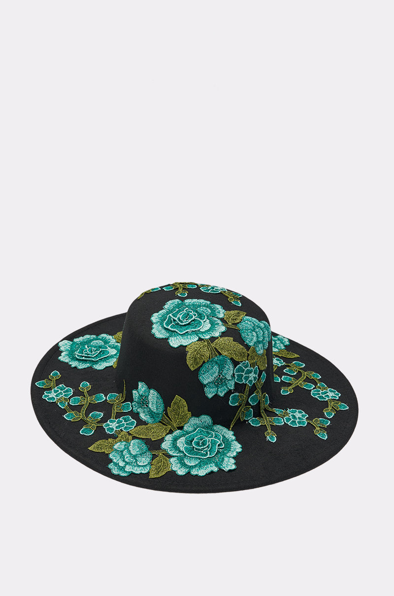 Make a statement with the IN THE FIELD APPLIQUE BRIM HAT—a black wide-brimmed hat adorned with teal and green embroidered floral patterns, featuring bold roses and leaves on the crown and brim. 2