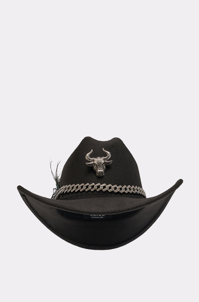 The LETS RIDE COWBOY HAT is a black hat featuring upturned brims, a silver bull head emblem, a silver chain band, and a small feather on the side, displayed against a plain white background. 1
