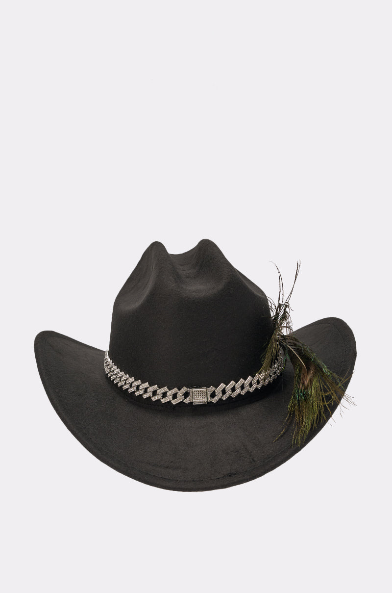 The LETS RIDE COWBOY HAT is a black wide-brim hat featuring a silver chain band and a cluster of green and brown feathers on one side, shown against a plain white background. 3