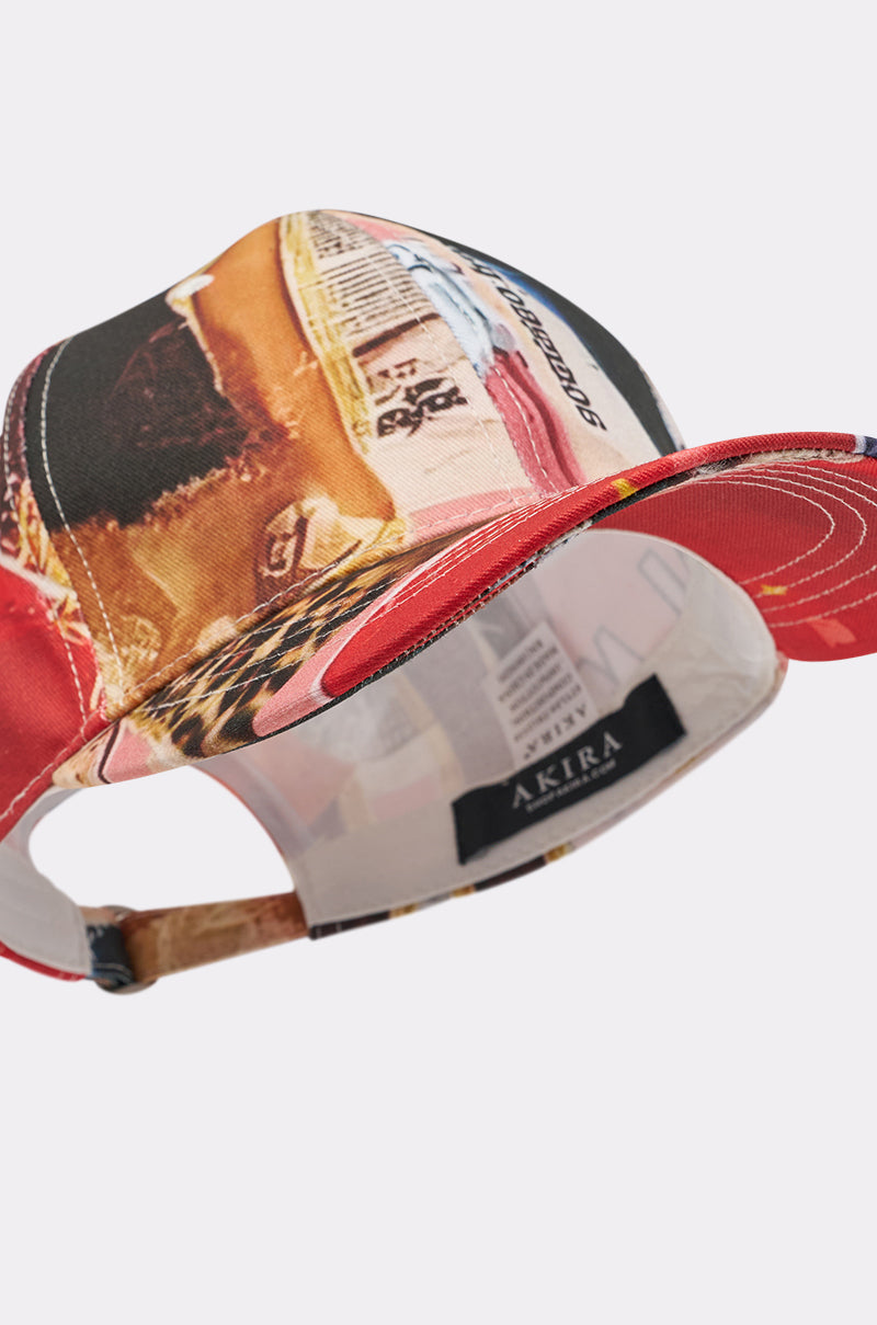The IN THE ZINE PRINT HAT is a street-style baseball cap with a vibrant magazine-inspired print, curved brim, adjustable back strap, and an interior label reading "AKIRA. 6