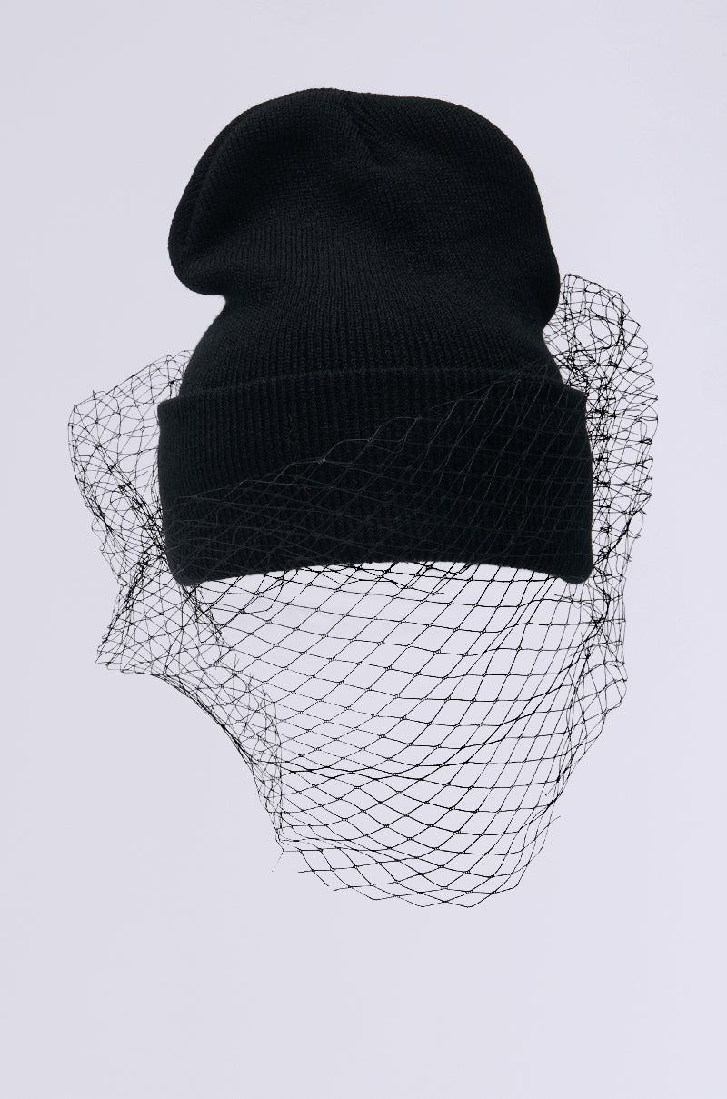 The ROCKY MESH VEIL BEANIE, a black beanie with a tonal mesh fishnet and ribbed knit base, drapes elegantly against a plain light gray background.
