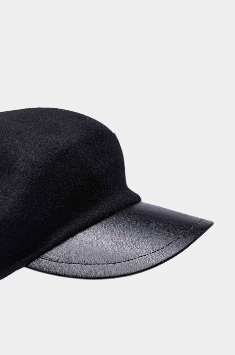 The FRENCH DREAM BERET BRIM HAT features a soft black fabric crown and a smooth, curved leather visor, displayed against a plain light background.