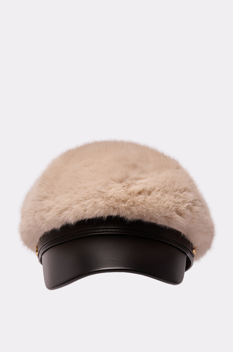 The IN THE CITY FUR BRIM HAT is a stylish faux fur fisherman cap with a wide, fluffy beige top and sleek black leather brim, shown against a plain light background.