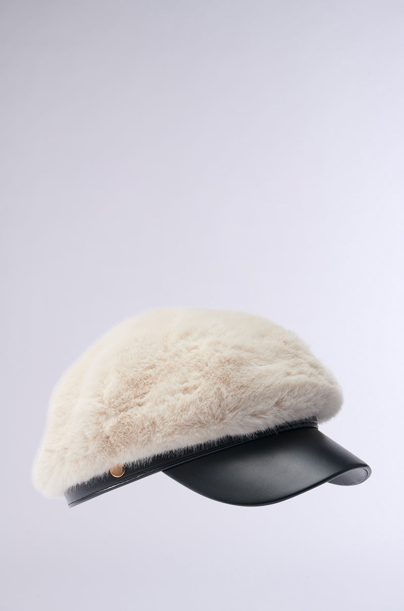 Discover the charm of the IN THE CITY FUR BRIM HAT, featuring a plush beige top paired with a chic black visor. This faux fur design perfectly balances its textured crown with a sleek brim, creating an effortlessly fashionable accessory.