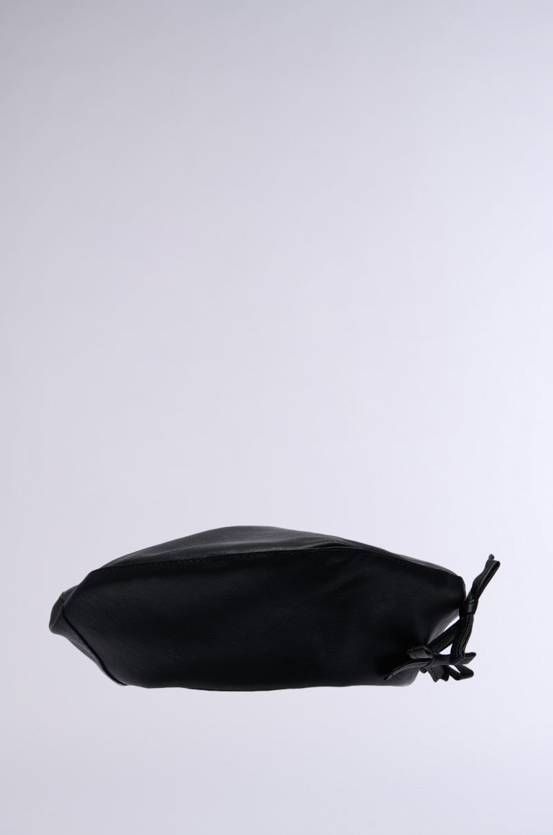 A sleek black PRETTY IN PU BOW BERET pouch sits against a plain, light gray background, clutched closed with an adjustable drawstring on one side, creating a slightly crinkled appearance in its otherwise smooth surface.