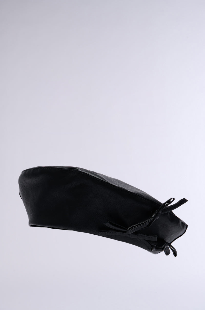 The PRETTY IN PU BOW BERET is made from faux black leather and presented on a simple white background. It features a sleek, smooth texture with a small bow accent on one side. For an ideal fit, it comes with adjustable drawstrings for added convenience. 4