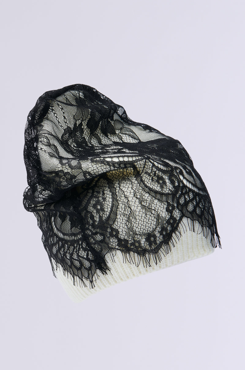 The LACED UP BEANIE features intricate floral lace patterns, providing a delicate and elegant look over its light, textured fabric.