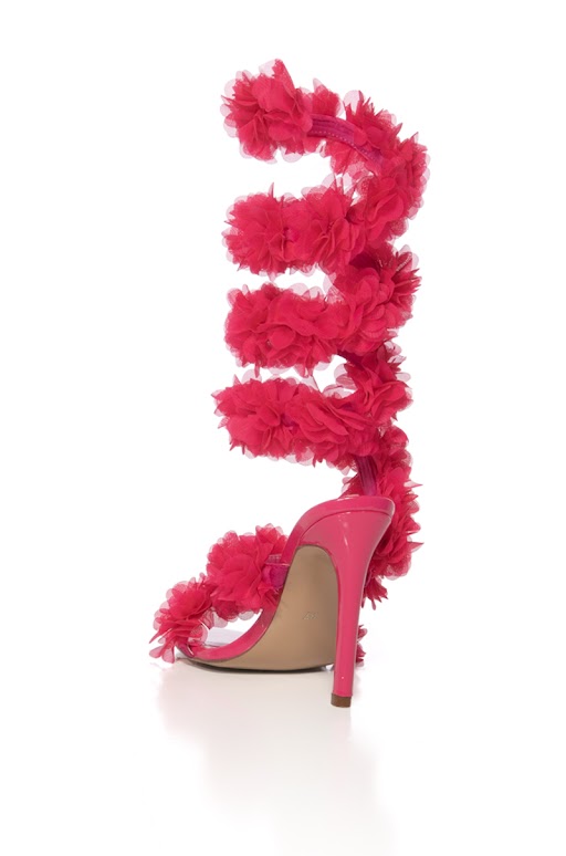 The AZALEA WANG THEODOSIA PINK STILETTO SANDAL is a glossy, high-heeled sandal in bright pink, featuring multiple straps with large floral appliques swirling above the ankle and a striking stiletto heel.
