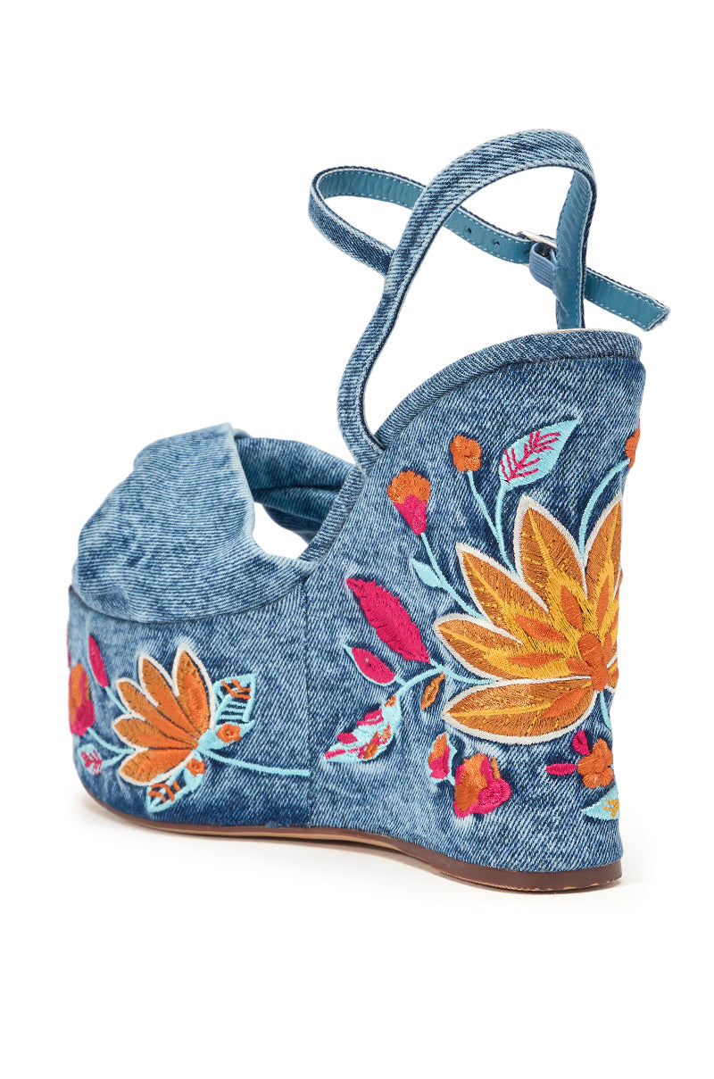 The AZALEA WANG TIALA DENIM FLORAL EMBROIDERED STRAP WEDGE SANDAL is a blue denim platform heel with ankle straps, featuring orange, yellow, and pink floral embroidery on the heel and sides. 6