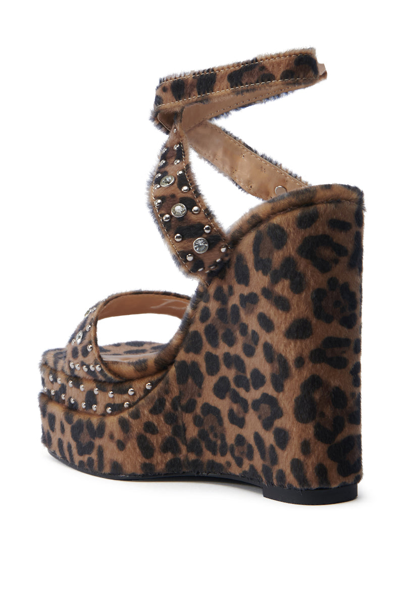 The AZALEA WANG TIBIL Leopard Wedge Sandal features a striking spotted pattern, thick ankle strap with silver studs, platform sole, closed back, and open-toe design.