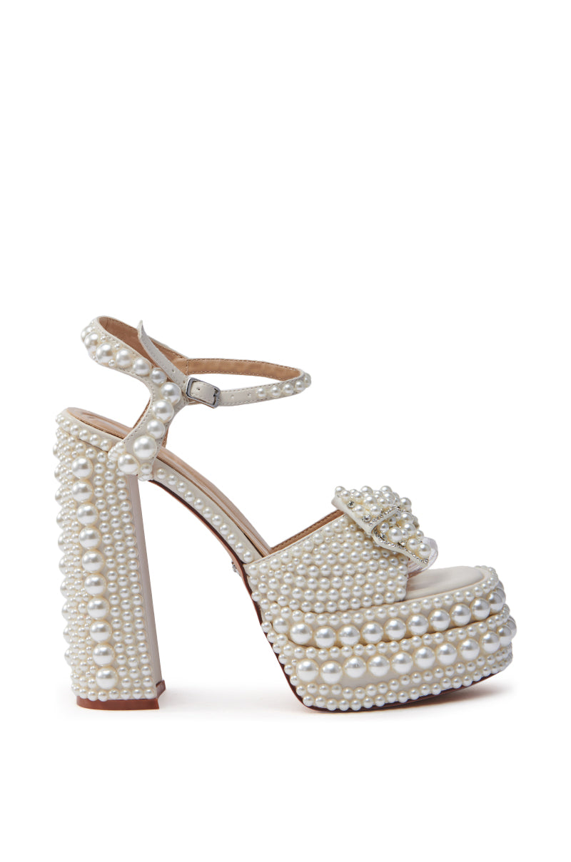 The AZALEA WANG TIMEA WHITE CHUNKY SANDAL has an ankle strap and platform sole, adorned with rows of small pearls. This white shoe features a decorative buckle at the toe and a thick heel covered in pearls, making a bold statement.