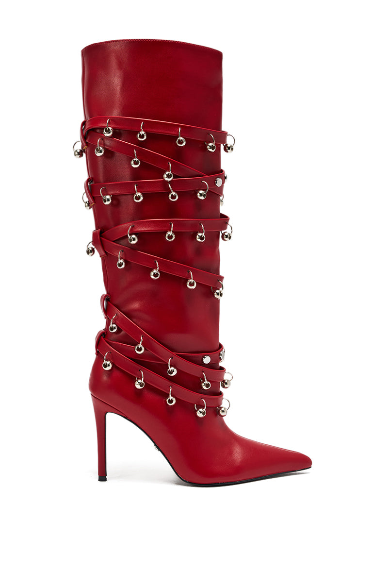 The AZALEA WANG TIMPANI Red Western Fringe Stiletto Boot features a tall faux leather design with a pointed toe, wraparound straps, silver rings and studs, all in a bold red finish.