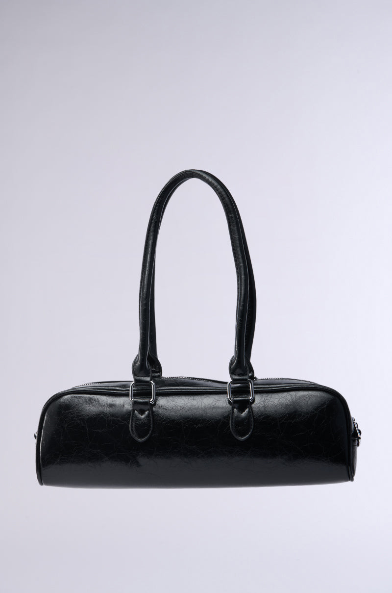 The BADDIE BARREL BAG in black faux leather is shown on a light gray background. Featuring two long handles, a detachable shoulder strap, smooth shiny texture, and minimalist design, it offers both style and versatility.