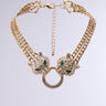 Introducing the ROARING 20S NECKLACE: a gold choker adorned with rhinestone cheetah head pendants encrusted with diamonds and green gemstone eyes. This exquisite necklace features a central ring connecting the heads, a gold double chain link, and an adjustable clasp at the back—an ideal accessory for any Great Gatsby-inspired ensemble.