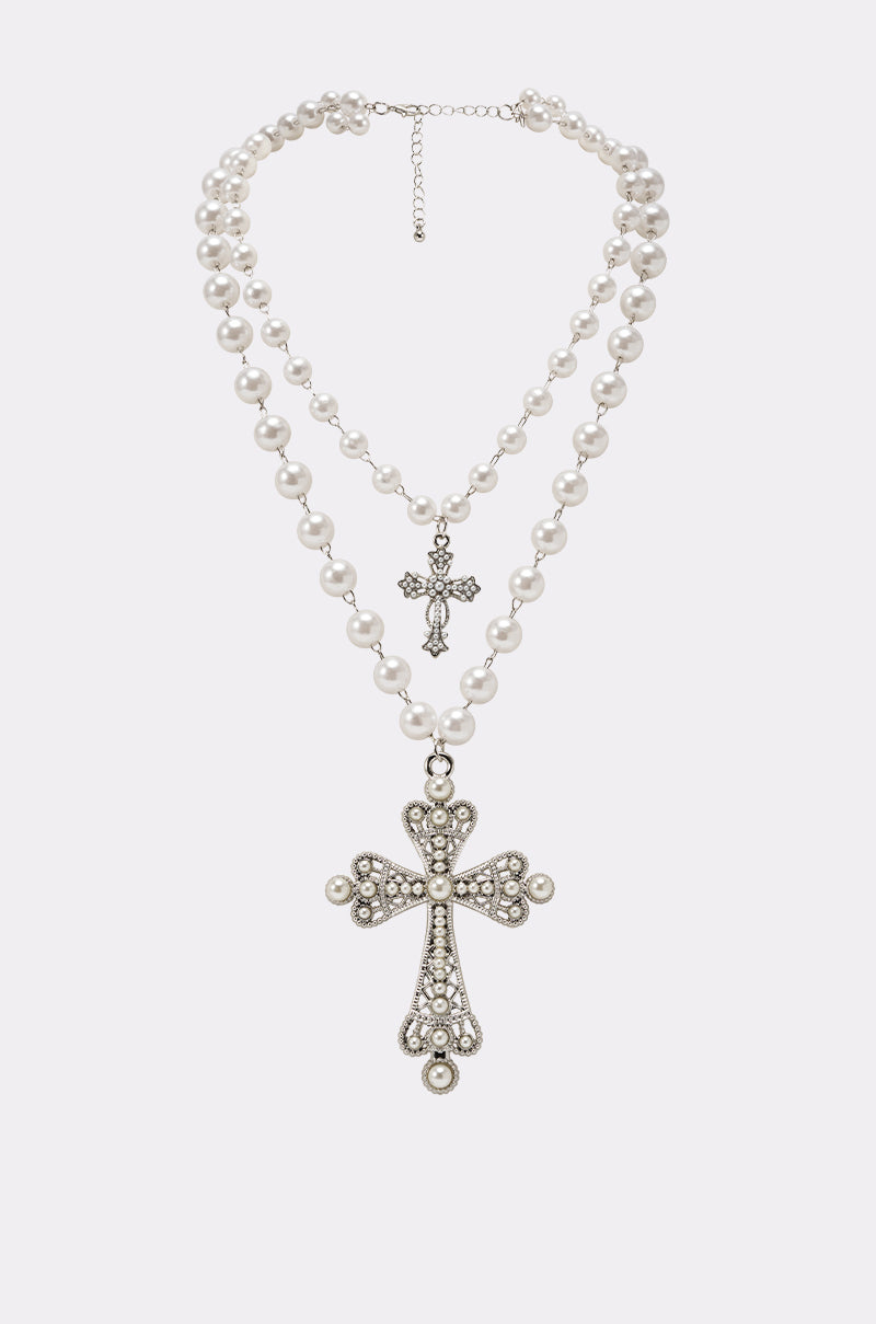 The IN MY DREAMS NECKLACE is a double-strand layered faux pearl necklace with two jeweled cross pendants, each adorned with sparkling rhinestones for an elegant touch against the white pearls. 0