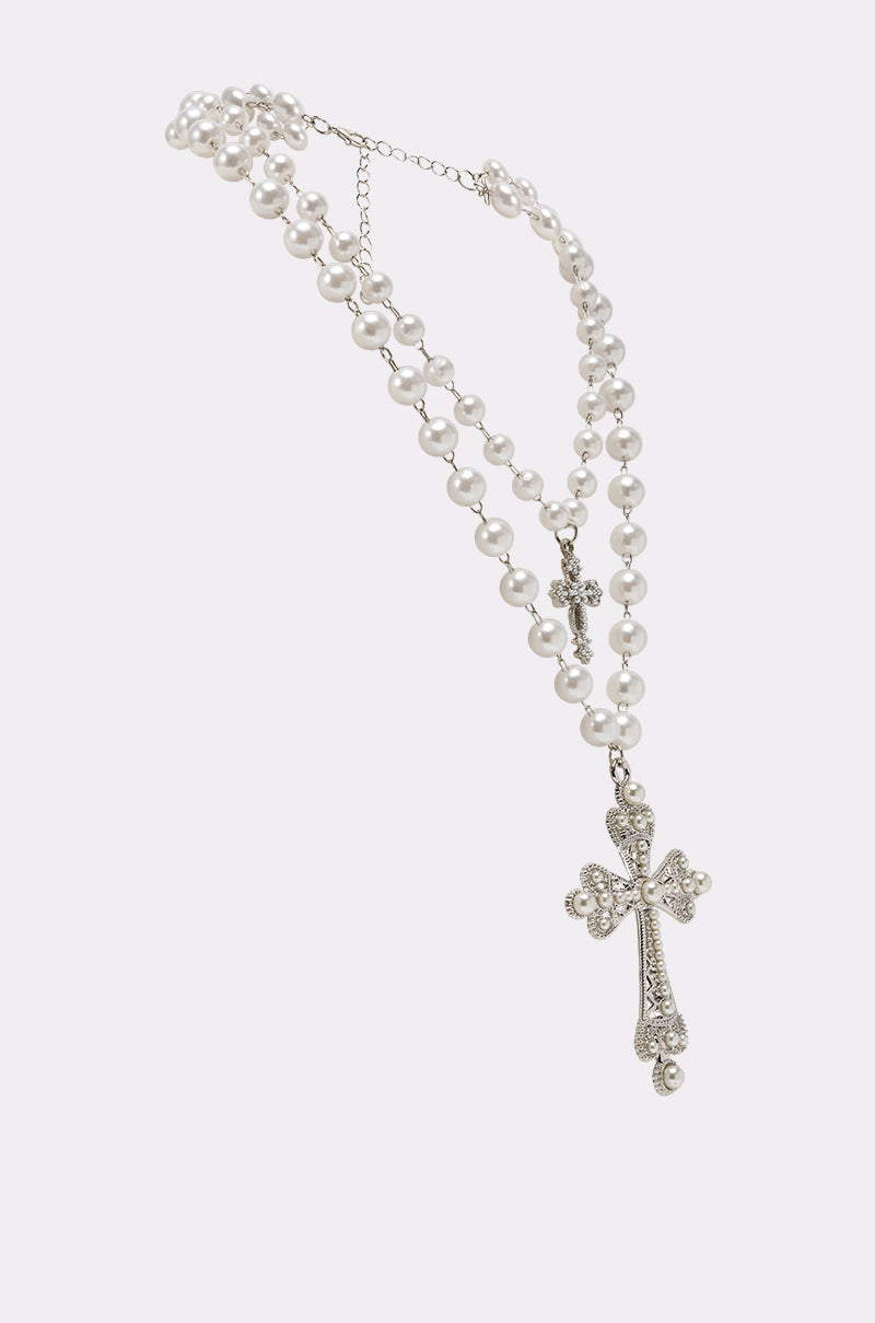 The IN MY DREAMS NECKLACE is a double-strand piece with silver chain details, layered faux pearls, and two ornate cross pendants (one large, one small), shown against a simple light background. 2