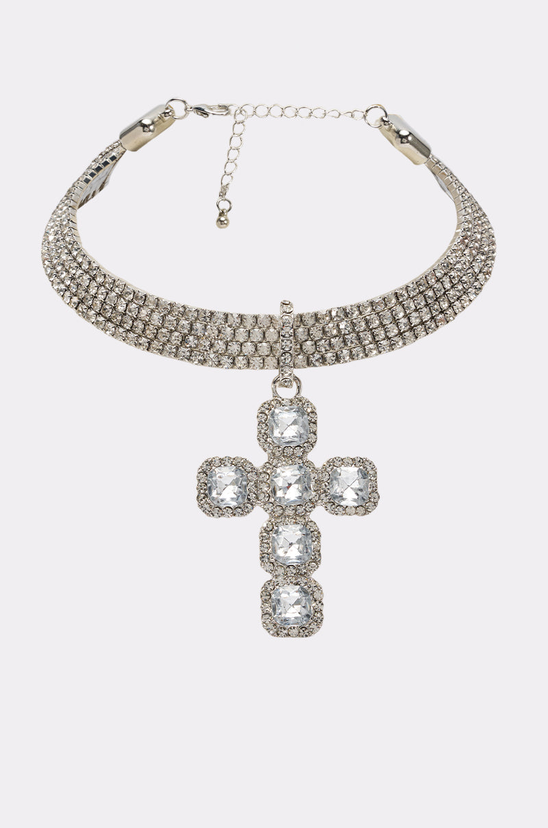 The LUXE AND LAVISH NECKLACE is a silver-tone collar necklace featuring a large cross pendant adorned with square and round clear gemstones, showcased against a plain white background.