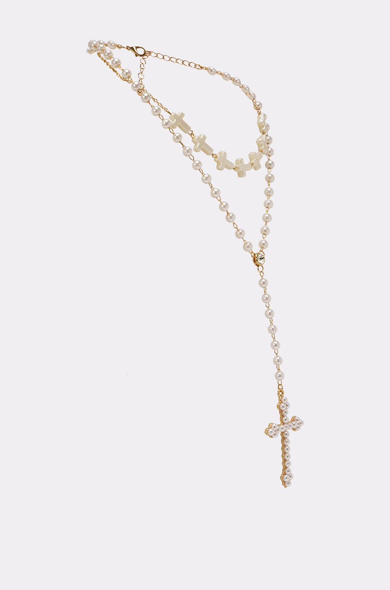 The IN YOUR DREAMS NECKLACE is a vintage-inspired gold and pearl rosary-style piece with pearl beads, a cross pendant, and an adjustable lobster clasp, shown against a plain white background. 3