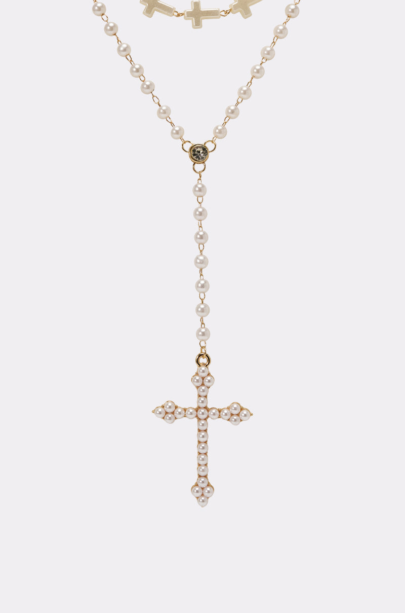The IN YOUR DREAMS NECKLACE is a vintage-inspired piece with a gold-tone chain, small pearls, and a pearl-accented cross pendant, beautifully displayed on a plain white background. 4