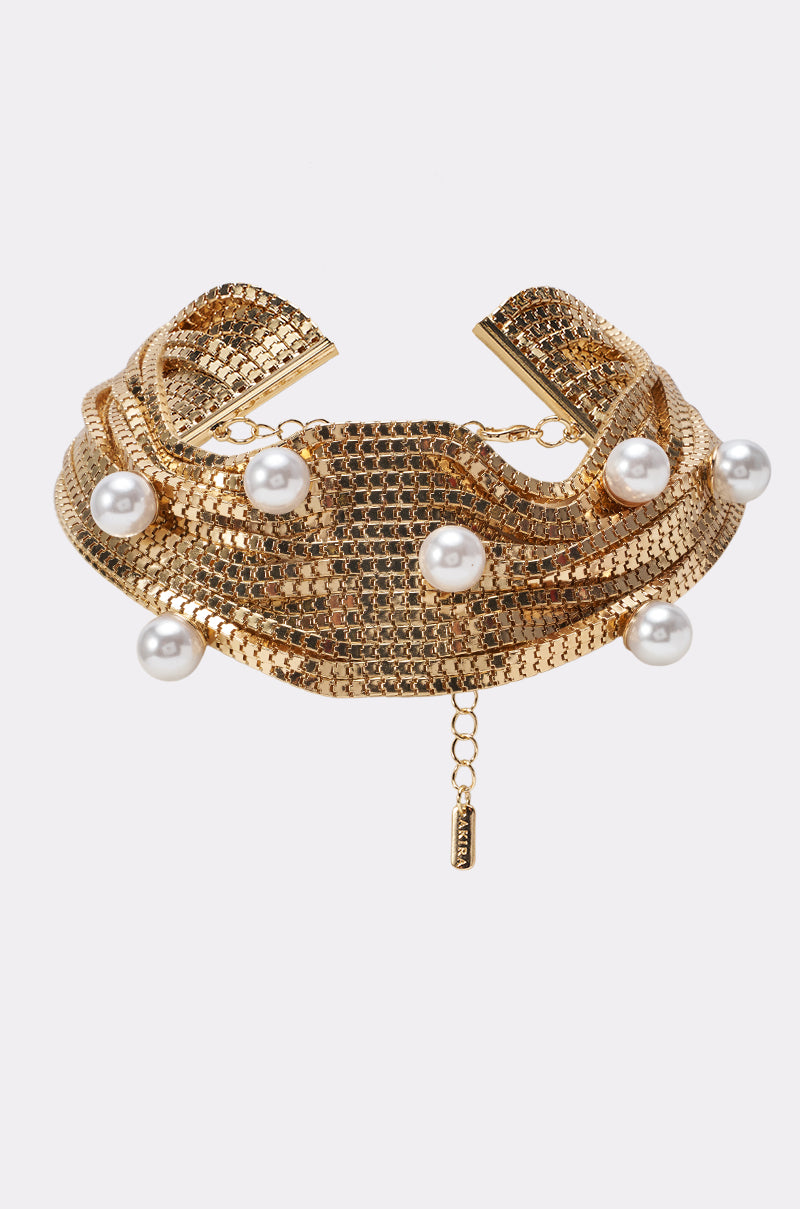 The PEARL PERFECTION NECKLACE is a gold mesh choker adorned with draped rows and spaced faux pearls, complete with a small gold tag and an adjustable chain for fastening—an elegant choice for bridal jewelry.