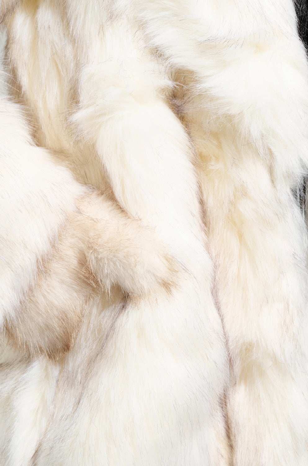 Close-up of the TOASTED MARSHMALLOW FUR COAT reveals its fluffy, soft faux fur in white and light beige hues. This textured surface features varying shades and lengths, evoking the cozy elegance of a maxi-length silhouette.