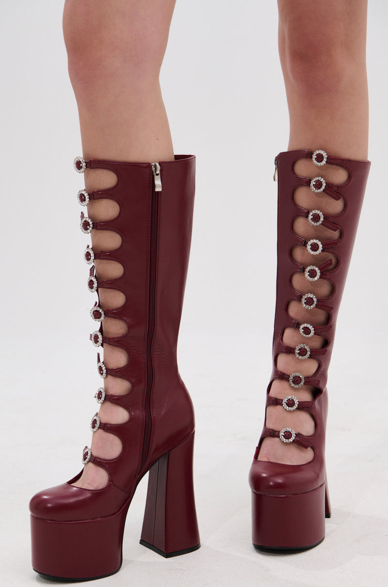 The AZALEA WANG TOMLIN BURGUNDY PLATFORM BOOT features faux leather, chunky heels, side zippers, and front cutouts with decorative round buckles that expose bare skin for a bold style.