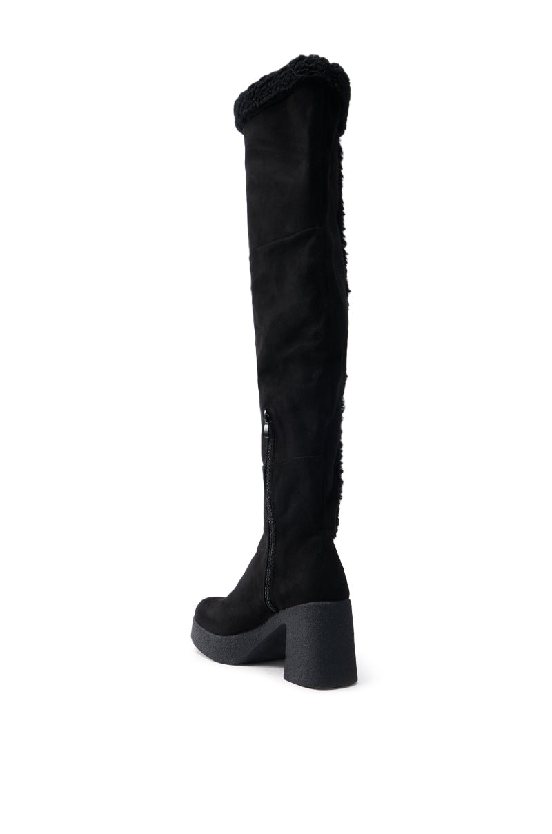 The TOP TIER BLACK CHUNKY BOOT is a thigh-high design with a faux suede texture, featuring a folded cuff at the top and a side zipper. Its chunky heel adds to its sturdy look.