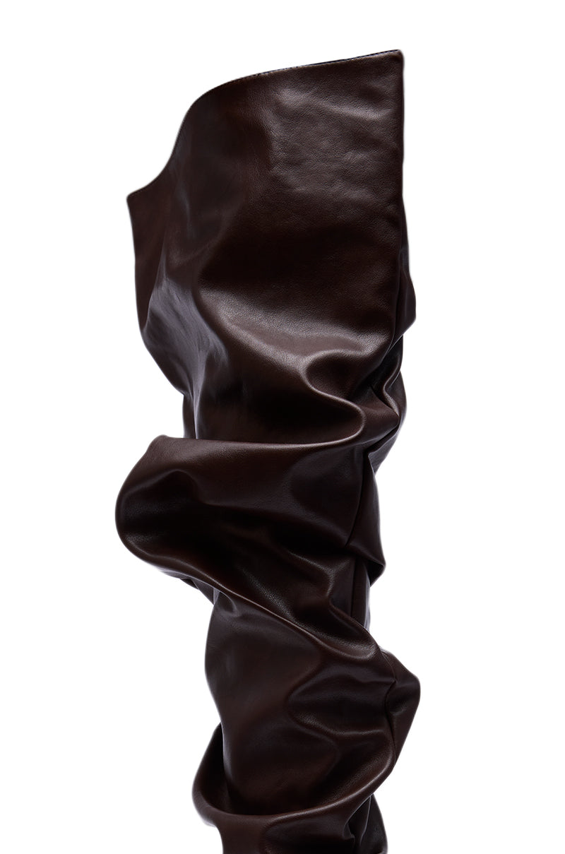 A close-up of the AZALEA WANG TORVIS CHOCOLATE SLOUCHY OVER THE KNEE BOOT, featuring tall dark brown faux leather with a glossy finish and bold ruching, set against a white background.