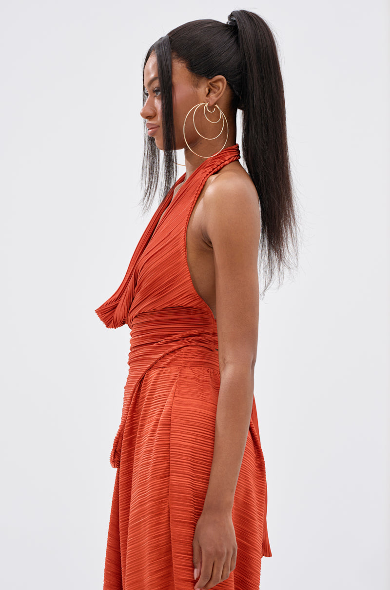 A woman with long, straight hair in a high ponytail wears large hoop earrings and the MAYAH Cowl Neck Plissé Sleeveless Top in red. She is shown in profile against a plain, light background. 3