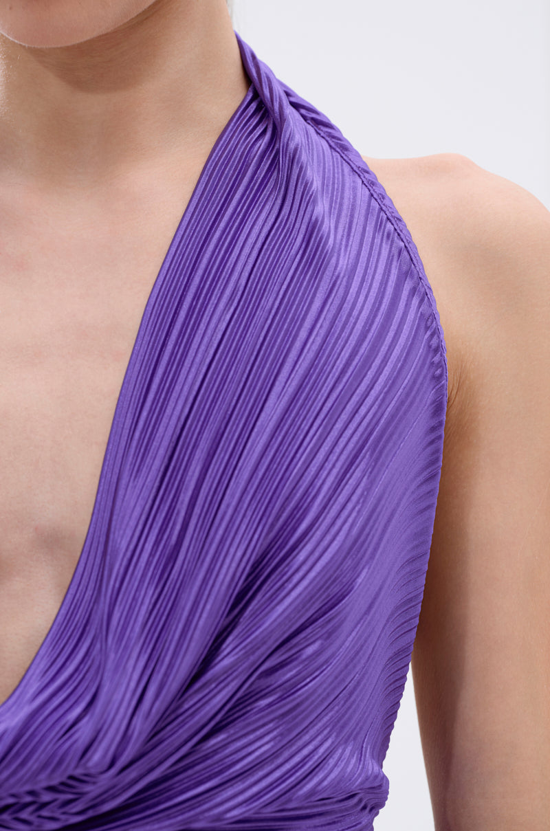 Close-up of a person wearing the MAYAH COWL NECK PLISSE SLEEVELESS TOP IN PURPLE, featuring elegant pleated fabric and a draped neckline. Only the shoulder, neck, and upper chest are visible. 8