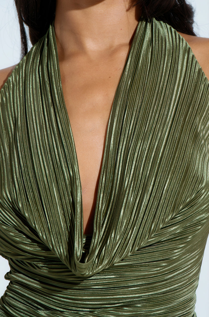 A person wearing the CROIX COWL NECK PLISSE HALTER TOP, an olive-green satin piece with a cowl neck and open back, highlights the fabric's shiny texture against a light background.