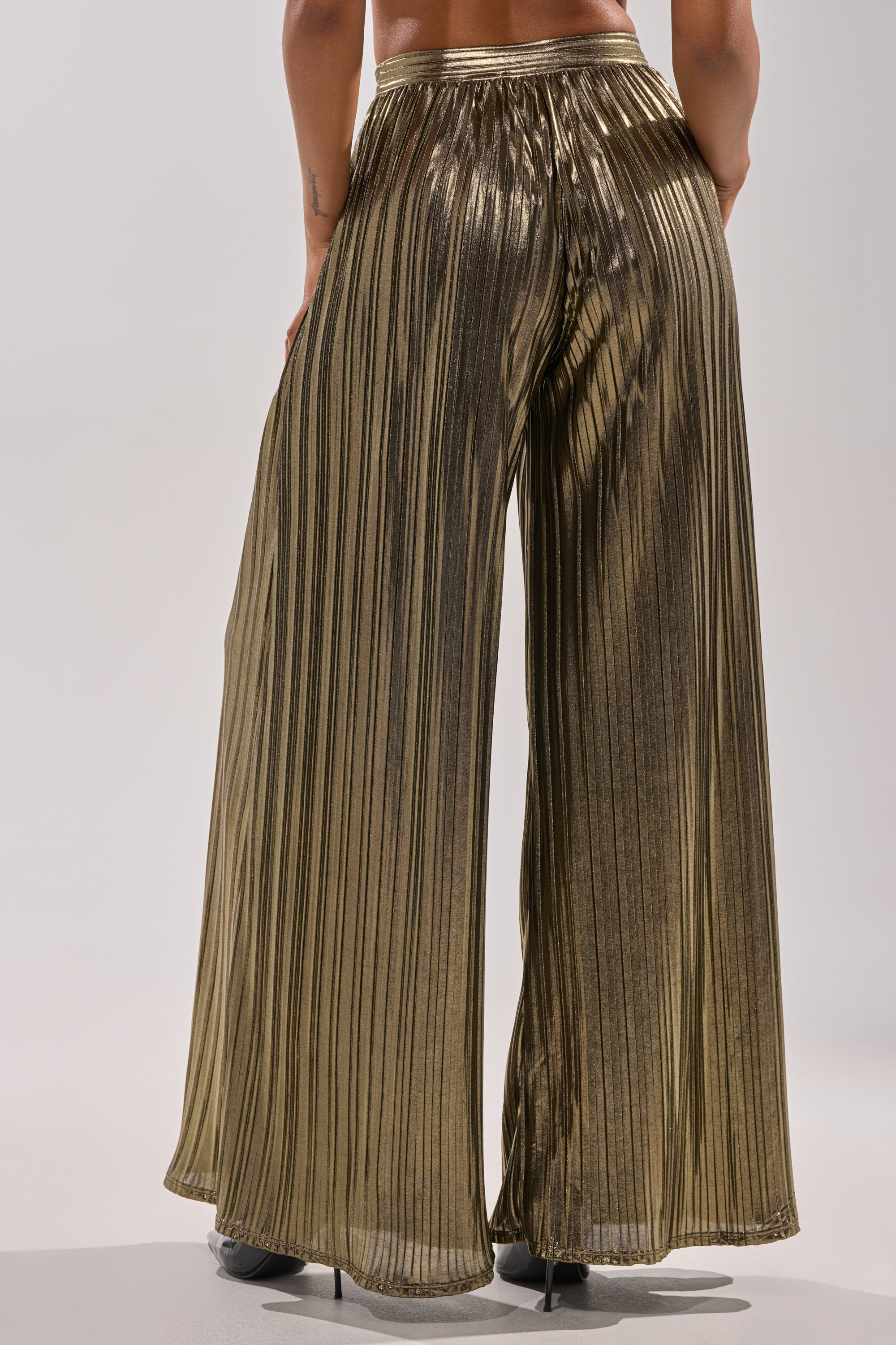 A person models the BEST DRESSED PALAZZO PANT in metallic pleats with black heeled shoes, shown from the waist down against a plain light background. 3