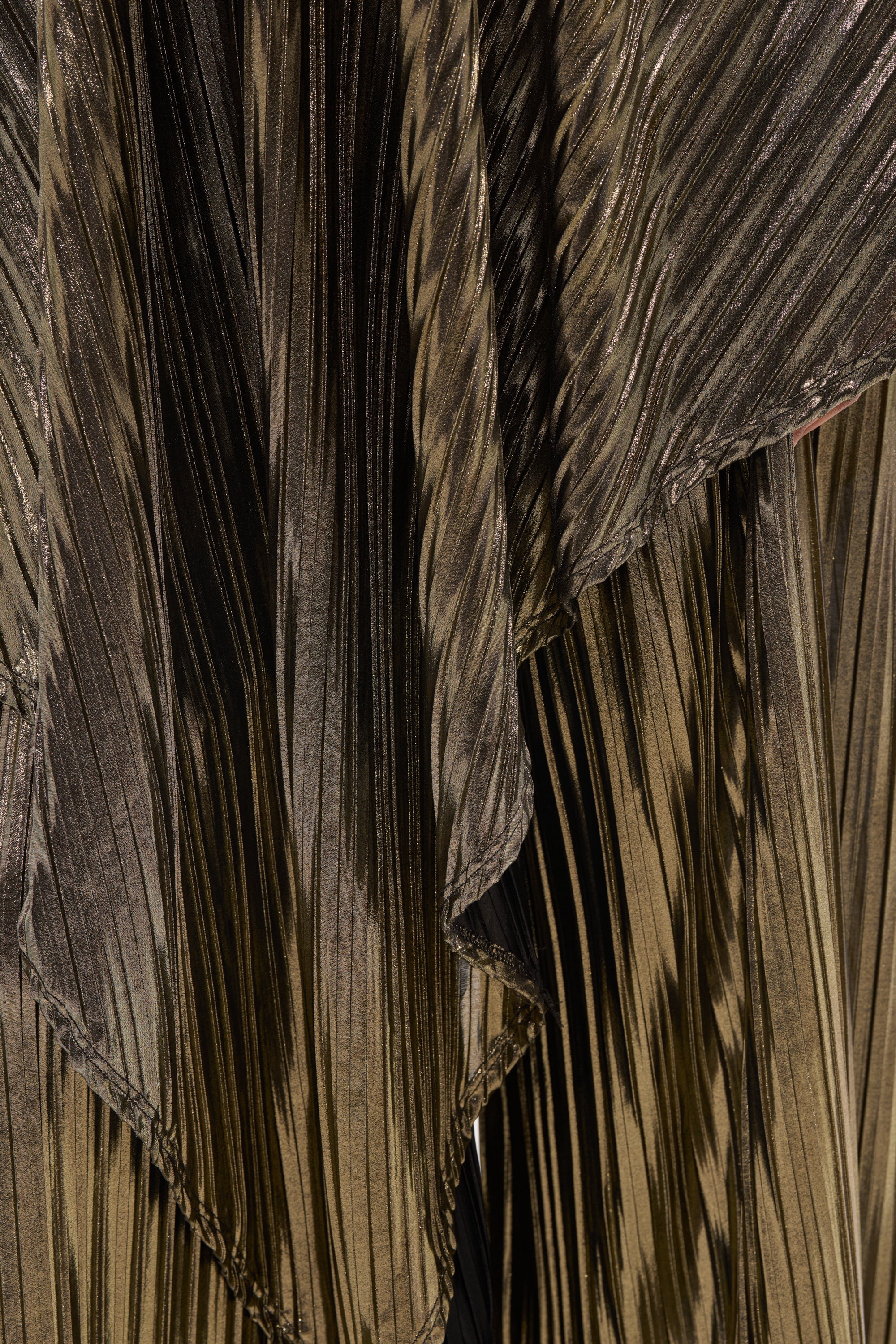 Close-up of the metallic gold pleated fabric featured in the BEST DRESSED BLOUSE, with textured layers and a reflective shine—ideal for an elegant evening look. 14