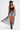 A woman wearing the SEE YOU LATER LACE BLOUSE, a black cowboy hat, denim shorts, and black cowboy boots walks confidently toward the camera against a plain white background.