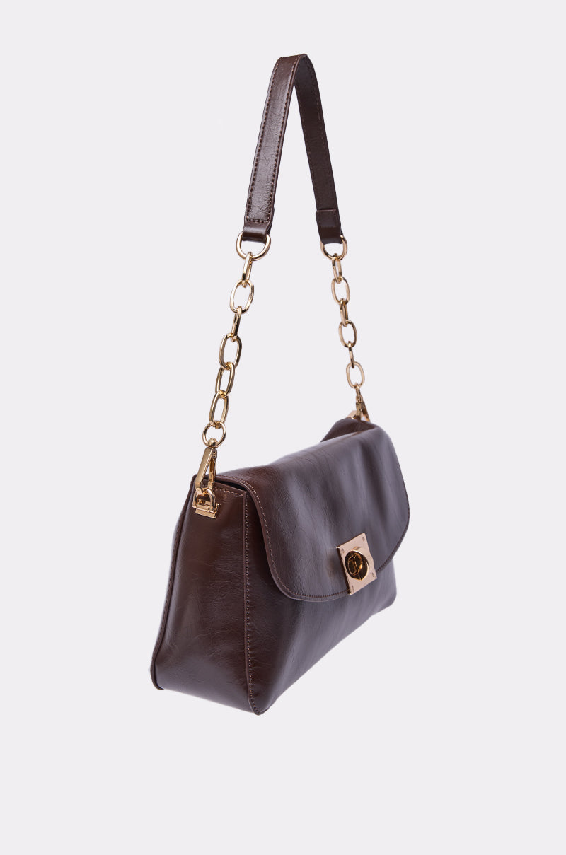 The BUTTER SOFT PURSE in dark brown faux leather features a flap closure, gold chain handle links, and a gold turn-lock clasp, displayed against a plain white background. 2