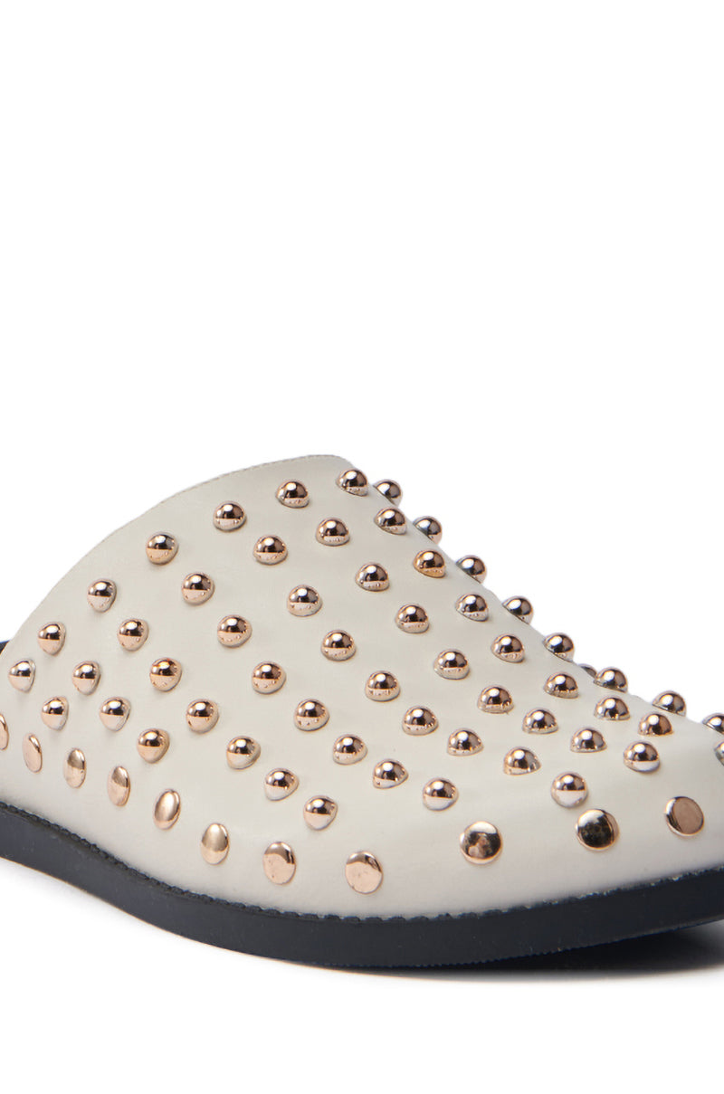The AZALEA WANG TRAVERSE BEIGE CLOG is a white slip-on crafted from vegan leather, featuring a grid of gold metallic studs and a contrasting black sole.