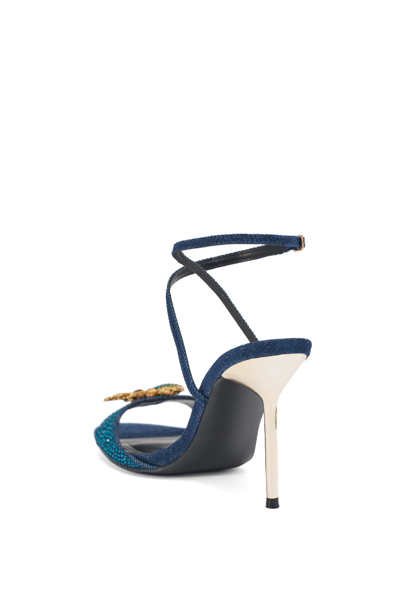 The AZALEA WANG TREETOK DENIM RHINESTONE STILETO SANDAL features a metallic stiletto heel, dark blue denim-textured straps, ankle buckle strap, and crystal-embellished front strap, shown from the back. 4