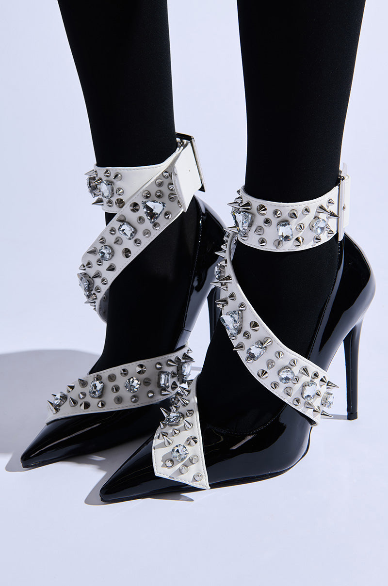 A bold and edgy look featuring black leggings paired with the AZALEA WANG TRIANA BLACK PATENT EMBELLISHED PUMPs, which boast embellished heels with shiny white straps adorned with silver spikes and studs.