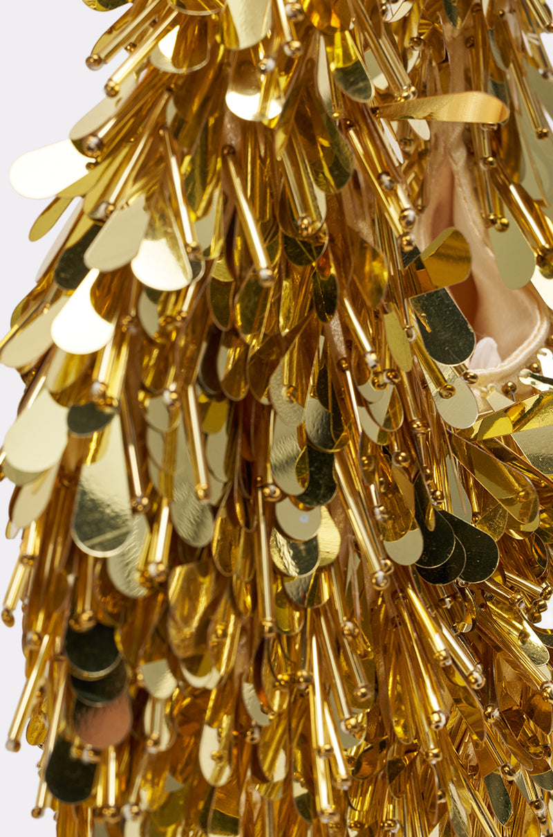 Close-up of THE NOSTALGIA SEQUIN PURSE IN GOLD shows densely layered gold sequins and rods, creating a festive, textured look. The shiny sequins catch and reflect light, giving the purse a sparkling, eye-catching effect.