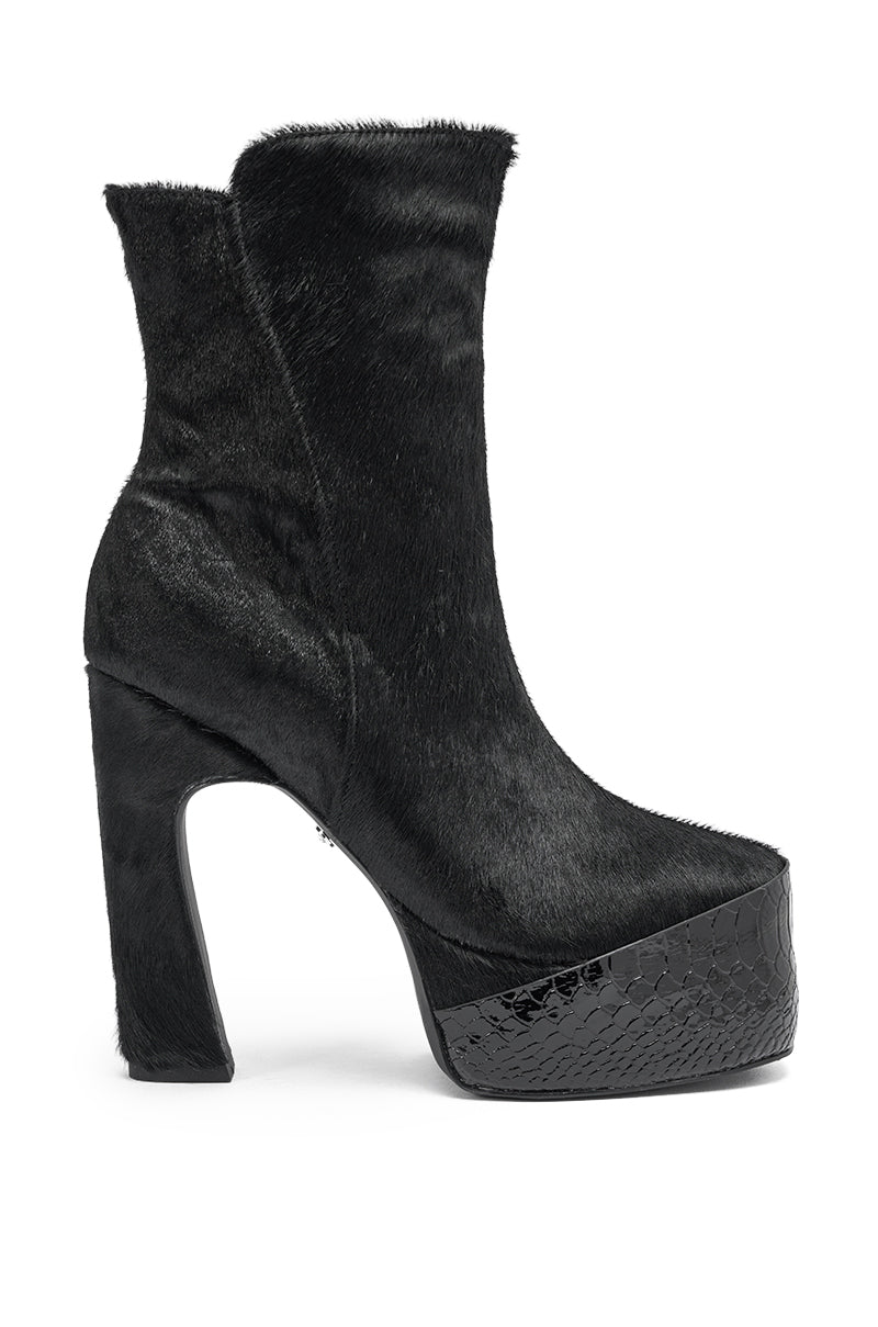 The AKIRA GOLD TROT BLACK BOOTIE features a high-heeled platform, a textured calf hair-inspired upper, and a glossy faux snakeskin platform and heel.