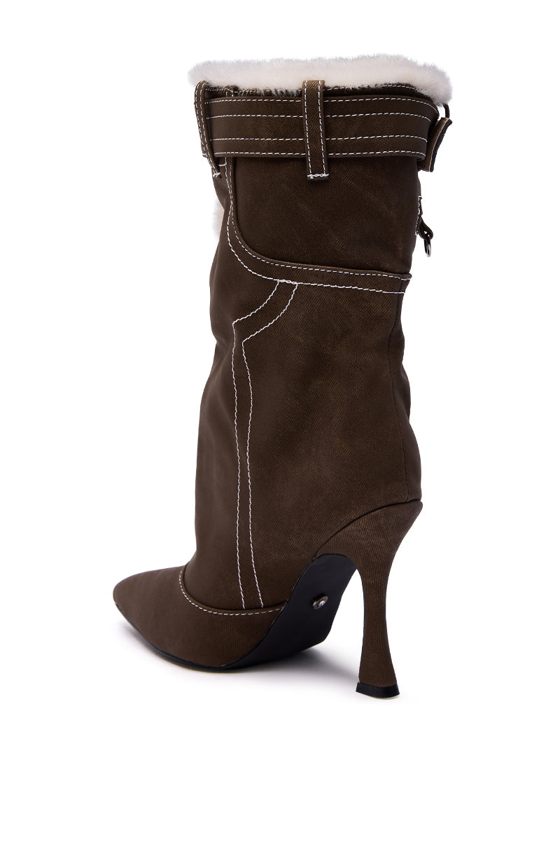 The AZALEA WANG TROYES Brown Sherpa Lined Pant Look Bootie features a brown suede stiletto heel, pointed toe, white stitching, mid-calf slouchy fit, side buckle detail, and cozy white faux fur lining at the top.