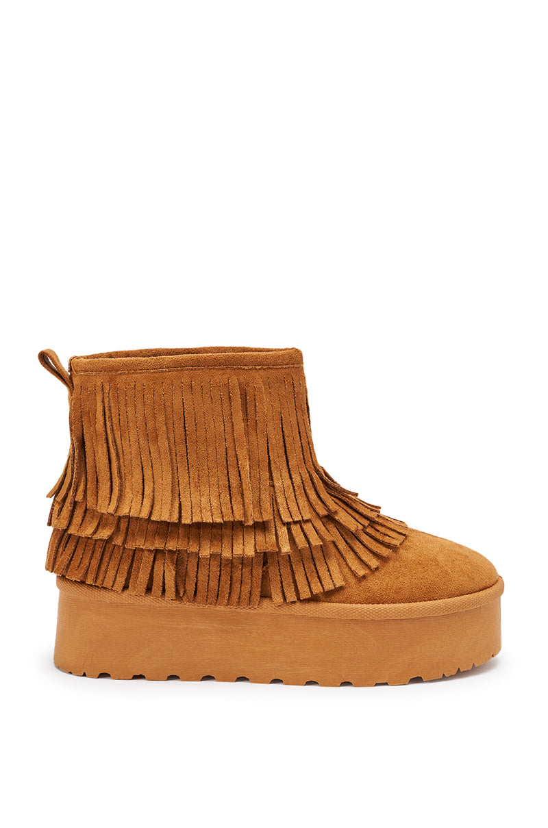 The AKIRA BROWN FAUX SUEDE FRINGE BOOTIE features a tan faux suede upper, thick flatform sole, layered fringe on the sides and back, pull tab at the heel, and a textured outsole for extra grip.