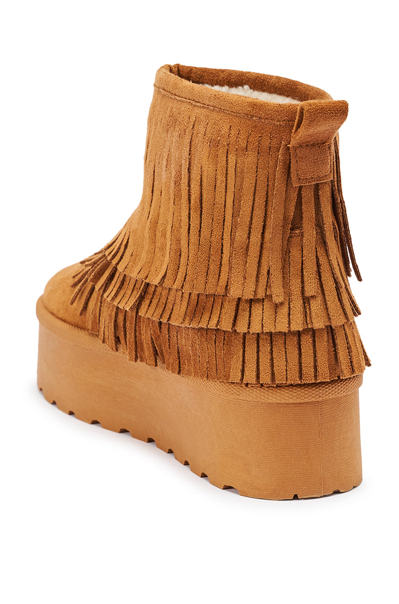 The AKIRA BROWN FAUX SUEDE FRINGE BOOTIE features tan faux suede, layered fringe, a back pull tab, and a thick flatform sole. Shown at an angle to highlight its side and back details.