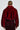 A person with a bun is wearing the NOW YOU SEE ME FAUX FUR BOMBER IN RED from AKIRA Label and a black skirt featuring red detailing, depicted from the back against a plain background.