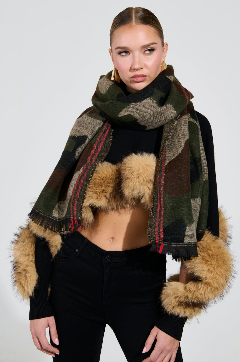 Wrapped in the fashionable CAMO NIGHTS SCARF and a cozy black-knit sweater featuring fur-trimmed sleeves, one completes the look with sleek black pants. Against a simple, light-colored backdrop, this ensemble's understated elegance truly shines.