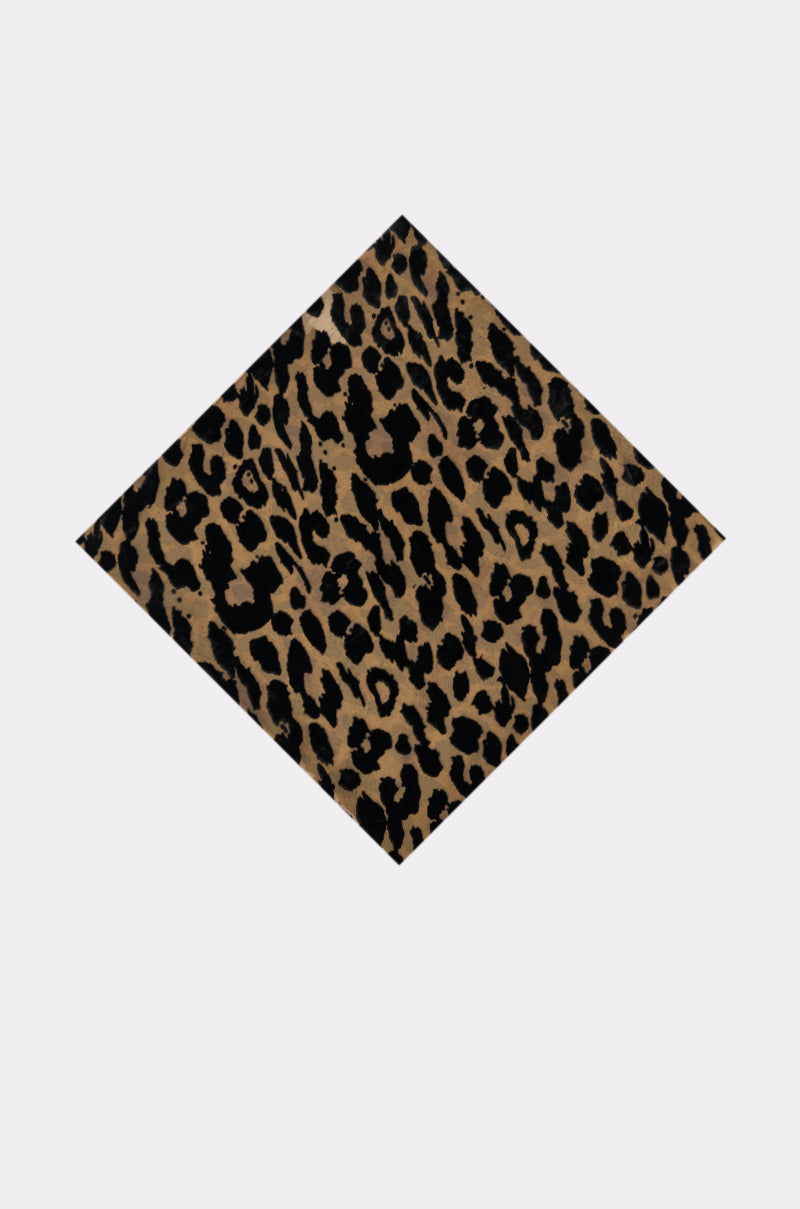 The TAKE ME TO ITALY HEADSCARF is a diamond-shaped scarf with black and dark brown leopard spots on a tan background, shown on a light backdrop—an ideal accessory for versatile styling. 1